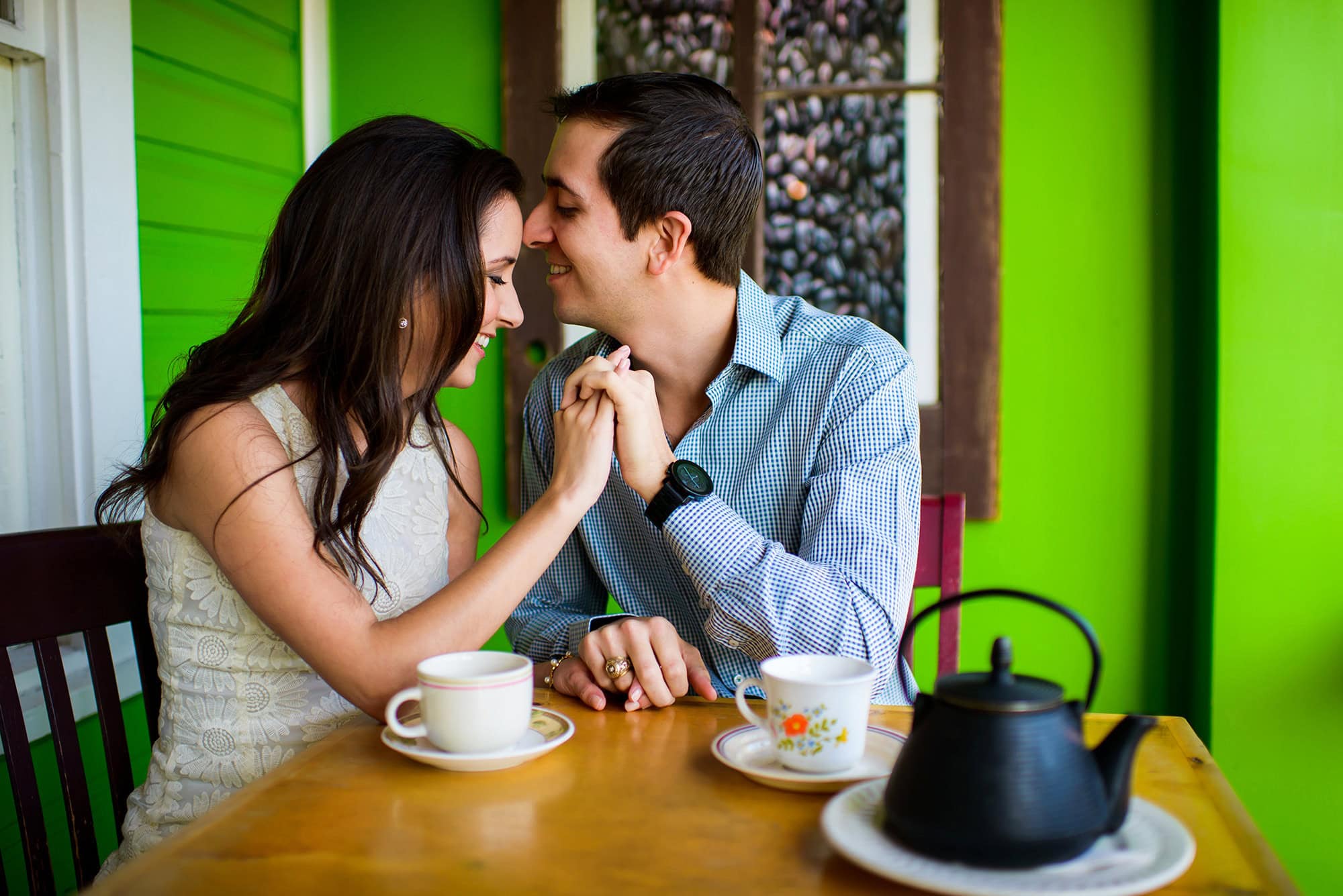 Couple share a sweet moment over tea during their San Antonio Engagement Session in a vibrant tea room