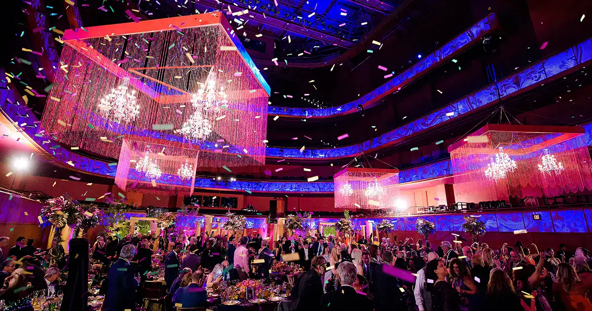 Elegant corporate event at the Tobin Center in San Antonio, TX with enormous chandeliers and confetti, with a New Orleans masquerade theme