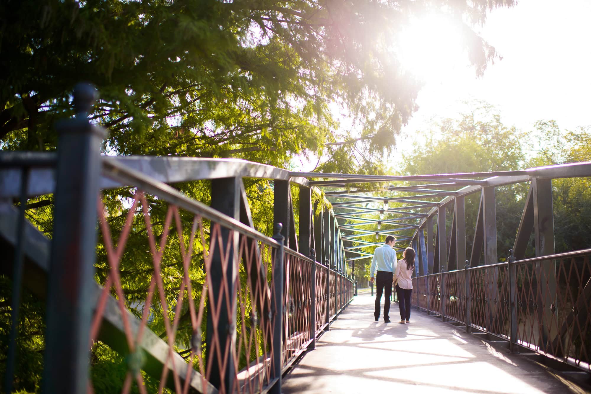 Vanessa & Matthew's Downtown San Antonio Engagement Session | couple holding hands walking across a bridge over the San Antonio riverwalk