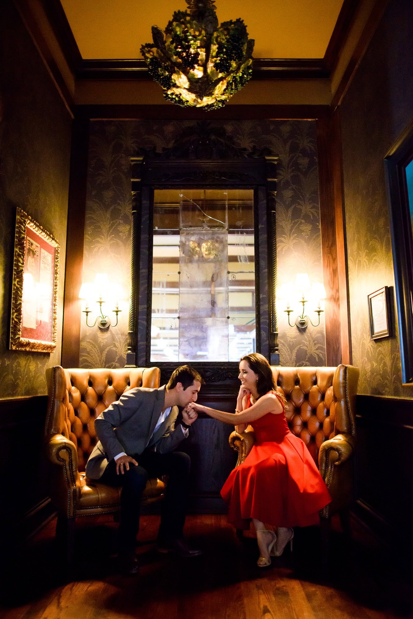 Vanessa & Matthew's Downtown San Antonio Engagement Session | man kissing woman's hand in tufted chairs at Bohanan's